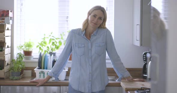 Serene woman standing in kitchen with arms crossed