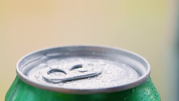 View of Manle Hand Opening an Aluminum Can of a Chilled Beverage Covered in Water Droplets