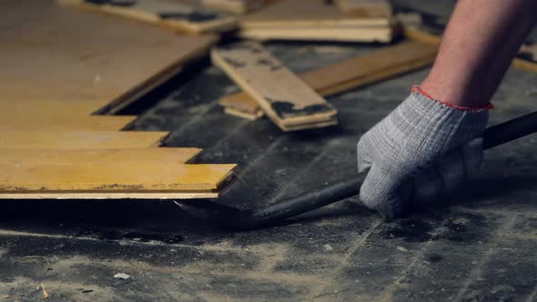 Worker Removes Old Parquet Using a Tire Iron Tool During a Flat Renovation