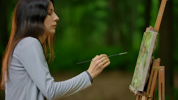 Attractive Girl Drawing a Landscape on the Nature in the Forest.