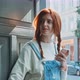 Attractive young woman with red hair using a smartphone at the door step - VideoHive Item for Sale