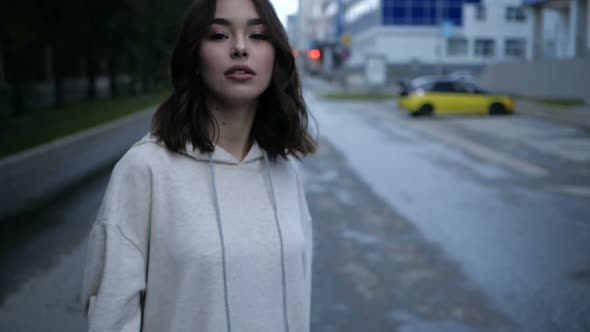 Video Portrait of a Girl Looking at the Camera with Dark Hair in a Beige Hoodie