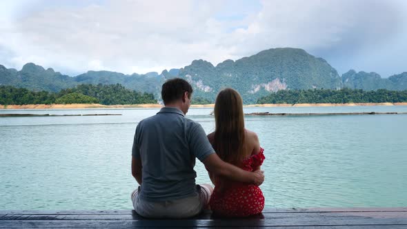 Couple on Date Sit on Lake Bridge Hugs Embrace and Putting Head on Shoulder