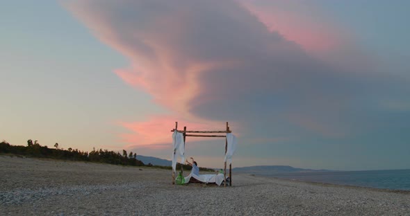 Young girl sleep on the gazebo bed during a insane sunset  on the beach