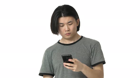 Portrait of Asian Guy with Clean Skin in Casual Gray Tshirt Responding on Sudden Call While Using