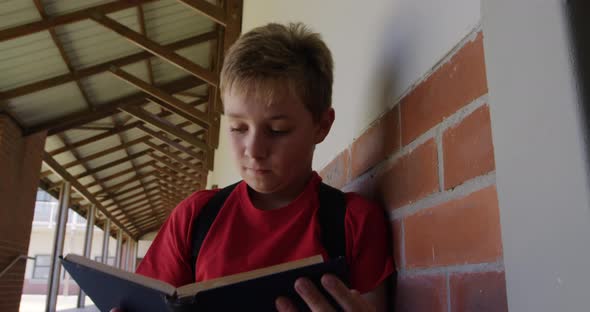 Boy reading books in the school corridor