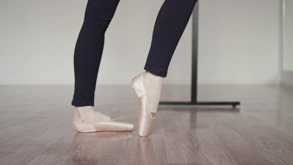 Ballerina's Legs in Pointe Shoes Closeup Alternately Stand on the Toe and Fall on the Heel
