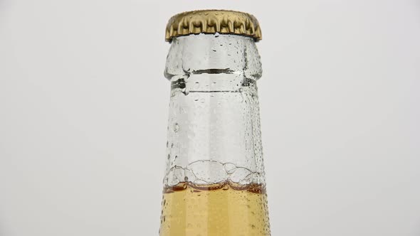 Glass bottle of beer frosty with water drops rotating