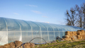 PVC tunnel greenhouse with hay bales used for insulation. - PhotoDune Item for Sale