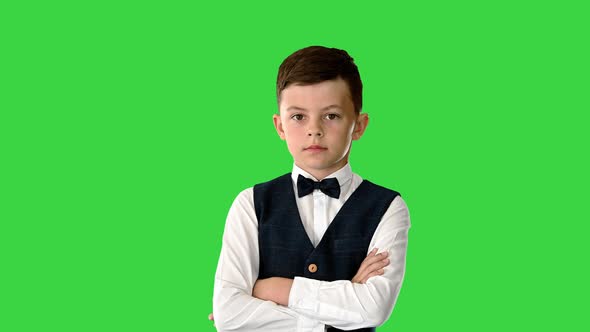 Young Boy in Bow Tie and Vest with Crossed Arms Nodding His Head While Looking at Camera and Saying