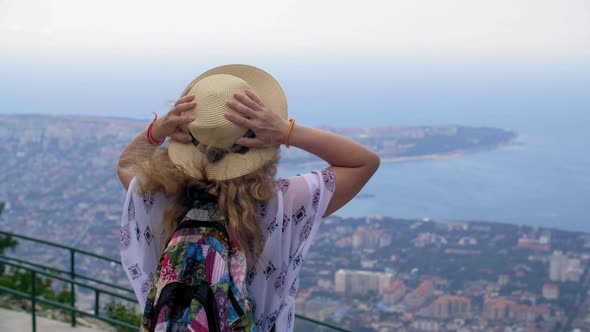 Back View of Woman in Hat Looking at Seascape and Coastal Town