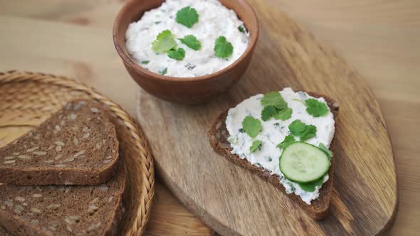 Toast with Cream Cheese and Cucumber on Wooden Plate