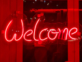 Closeup of red welcome neon sign hanging on the window of bar or night club - PhotoDune Item for Sale