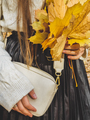 Closeup toned image of young stylish woman in sweater holding yellow autumn leaves in hands - PhotoDune Item for Sale