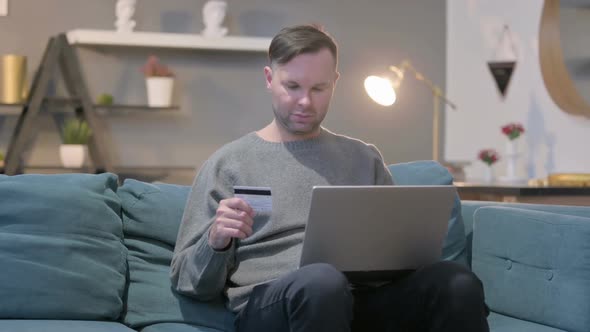 Casual Man with Unsuccessful Online Payment on Laptop on Sofa