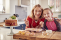 Portrait Of Grandmother With Granddaughter Baking Cupcakes And Putting Icing On Their Noses At Home - PhotoDune Item for Sale