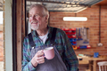 Portrait Of Senior Male Wearing Overalls In Garage Workshop With Hot Drink - PhotoDune Item for Sale