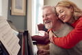Smiling Senior Couple At Home Enjoying Learning To Play Piano - PhotoDune Item for Sale