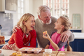 Grandparents With Granddaughter Eating Homemade Cupcakes In Kitchen At Home - PhotoDune Item for Sale