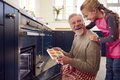 Grandfather And Granddaughter Take Freshly Baked Cupcakes Out Of The Oven In Kitchen At Home - PhotoDune Item for Sale