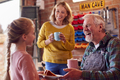 Granddaughter With Grandmother Bringing Grandfather Cake And Hot Drink In His Home Workshop - PhotoDune Item for Sale