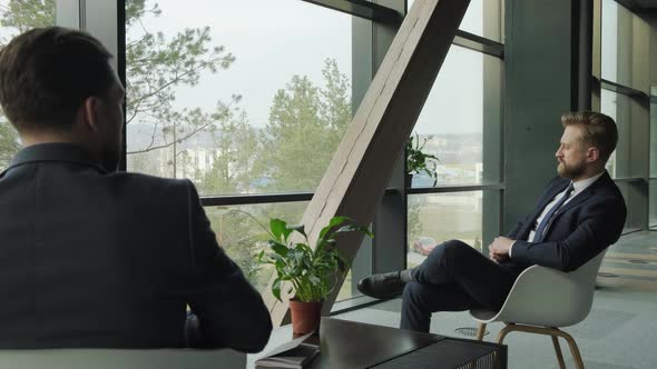 Close Up of Businessmen Sitting on Couches Discussing at Coffee Table