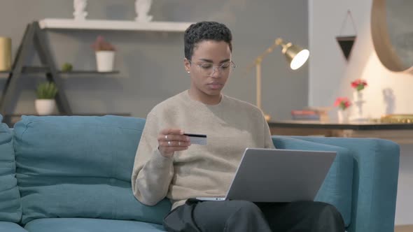 African Woman with Unsuccessful Online Payment on Laptop on Sofa