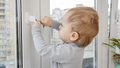 Little baby boy opens window safety lock with key. Baby in danger. Child safety and protection - PhotoDune Item for Sale