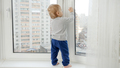 Little baby boy standing on windowsill and pulling window handle. Baby in danger. CHild safety. - PhotoDune Item for Sale