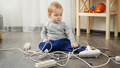 Little baby boy left alone playing with electric cables and wires. Child in danger - PhotoDune Item for Sale