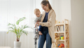 Young mother cleaning floor with vacuum cleaner while holding her little baby son. - PhotoDune Item for Sale