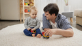 Smiling young man playing with his baby boy with toys at home - PhotoDune Item for Sale