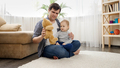 Happy smiling baby boy with father having fun and playing with teddy bear on carpet at home. - PhotoDune Item for Sale