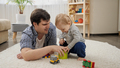 Little baby boy giving toys to his father for playing on carpet. - PhotoDune Item for Sale