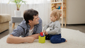 Cute baby boy playing with toys and his father on carpet at home. - PhotoDune Item for Sale