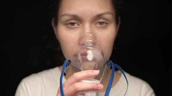 Young woman puts an inhaler mask on her face and treats the lungs