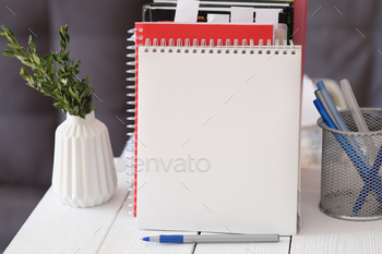 An open notebook with white pages and a pen. open page of the notepad with stationary