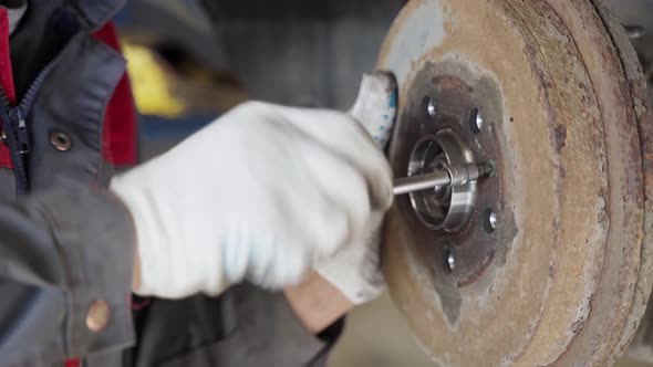 the Master Tightens the Centering Screw in the Car Brake Drum with a Screwdriver