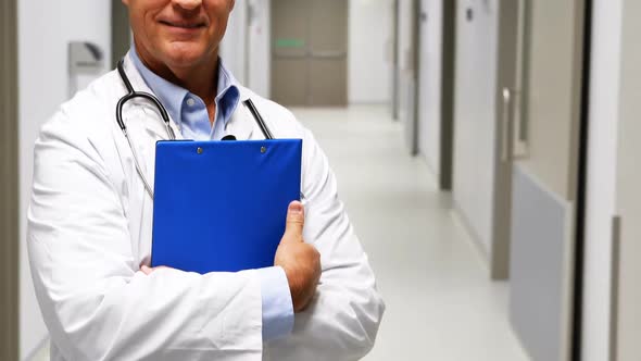 Portrait of doctor holding clipboard in corridor