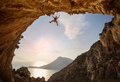 Female rock climber hanging on rope while lead climbing in cave with beautiful sea view - PhotoDune Item for Sale