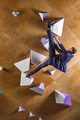 Young man in suit climbing difficult route on artificial wall in bouldering gym - PhotoDune Item for Sale