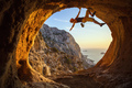 Young woman free solo climbing in cave with beautiful sea view in background - PhotoDune Item for Sale