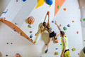 Rock climbers in climbing gym. Young woman climbing bouldering problem, man giving her instructions. - PhotoDune Item for Sale