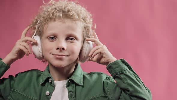 Little Blonde Boy Wearing Big Headphones and Nodding His Head