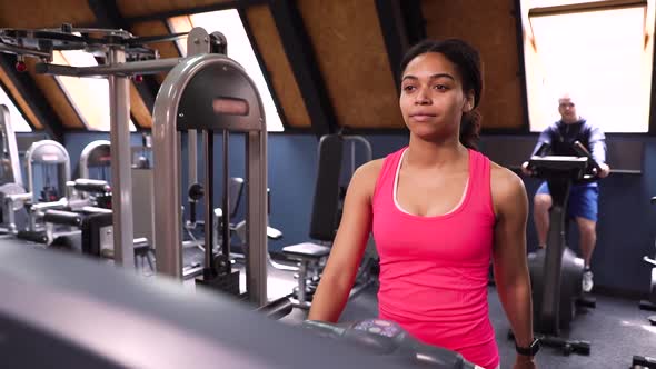 Black girl walking on treadmill and guy riding exercise bike in gym