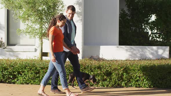 Happy caucasian couple is taking their dog for a walk