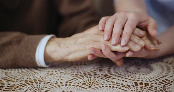 Woman Touching Elderly Man Hands and Supporting Senior Man