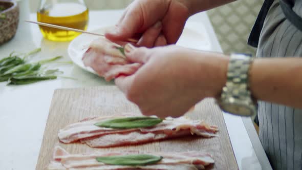 Woman putting raw saltimbocca on wooden stick