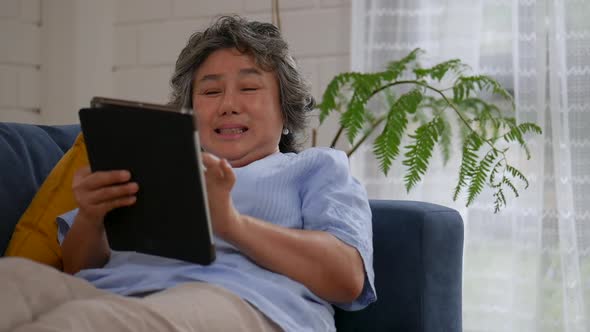 Portrait Asian senior woman using tablet searching online shopping.