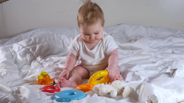 Adorable Eightmonthold Girl Playing with Pyramid Toy Sitting on the Bed